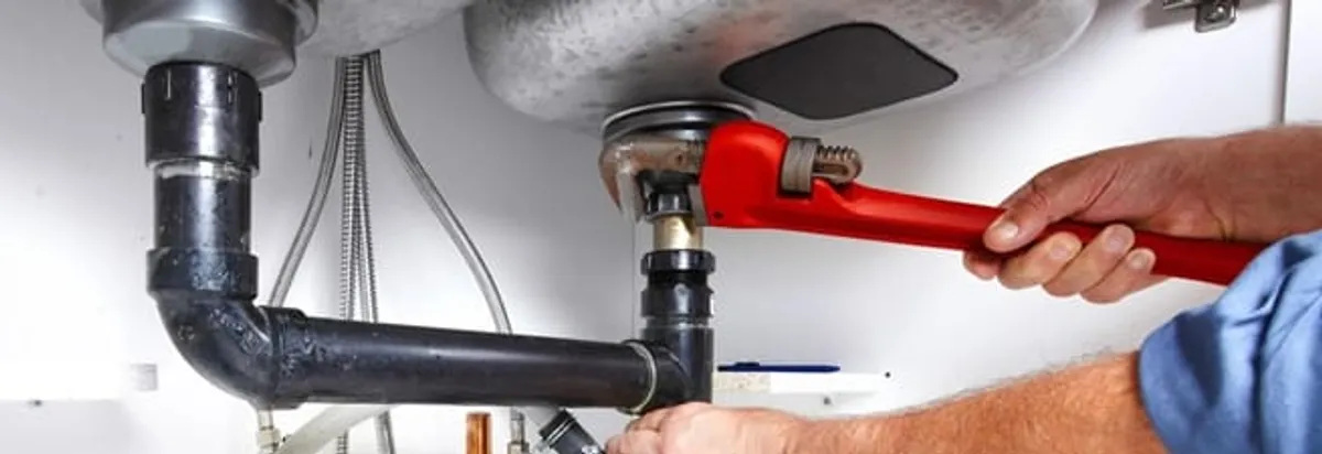 Garbage disposal repair technician tightening the sink drain and disposal connection in Savannah, GA