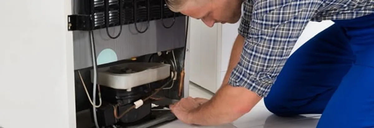 Refrigerator repair technician servicing the compressor and condenser area in Savannah, GA
