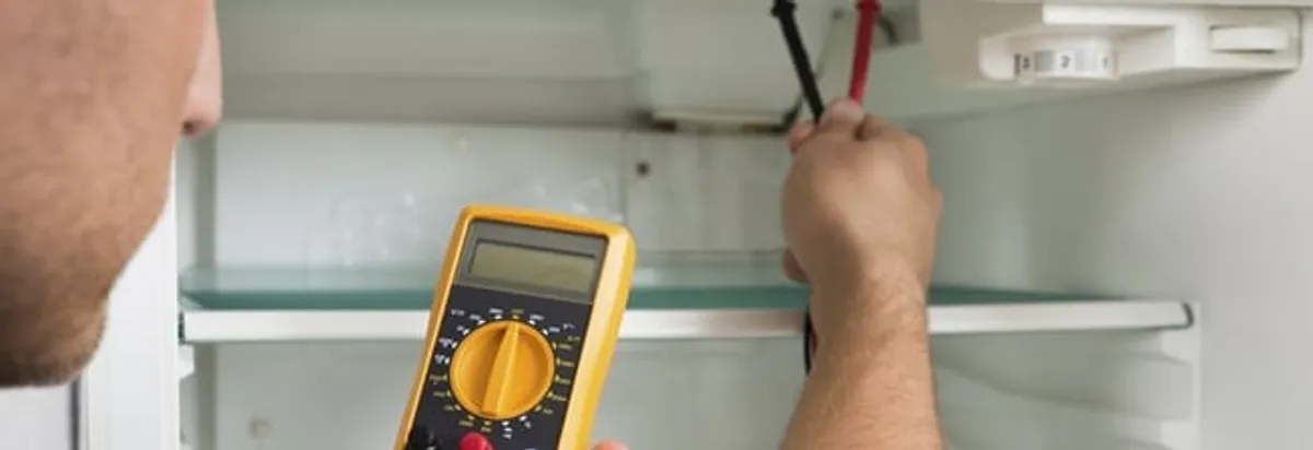 Refrigerator repair technician testing electrical components with a multimeter in Savannah, GA