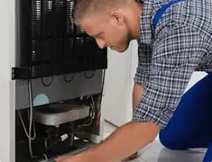 Refrigerator repair technician servicing the compressor and condenser area in Savannah, GA