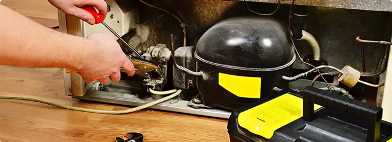 Refrigerator repair technician fixing the compressor and wiring in Savannah, GA